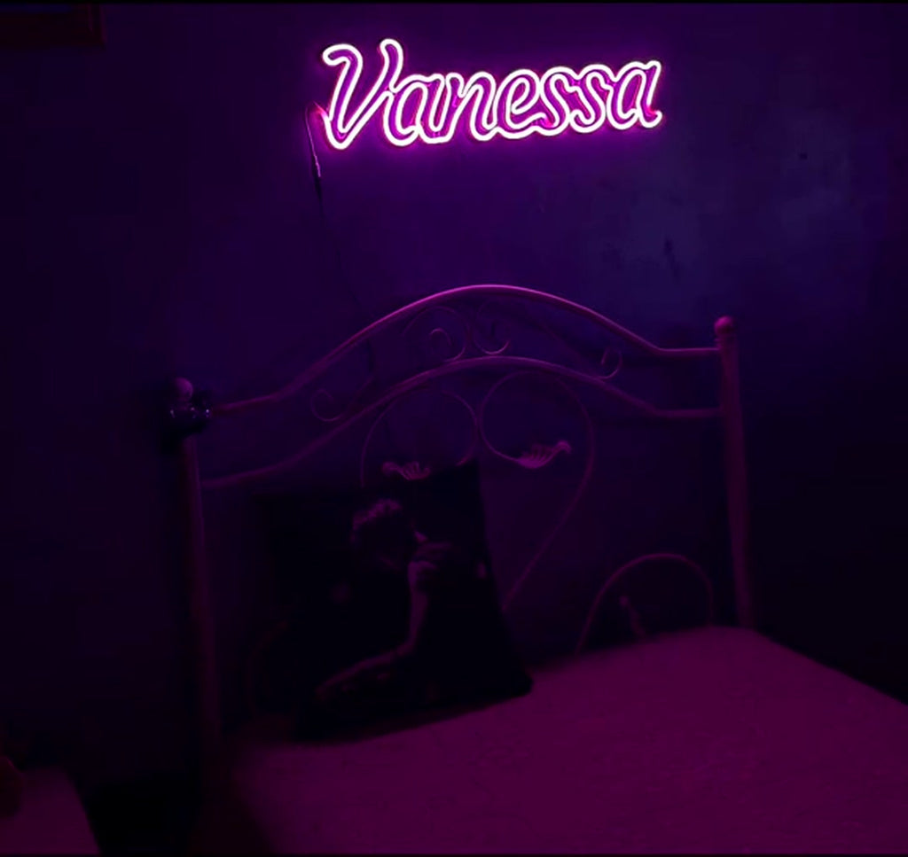 Scritta neon con nome Vanessa accesa sopra il letto in cameretta