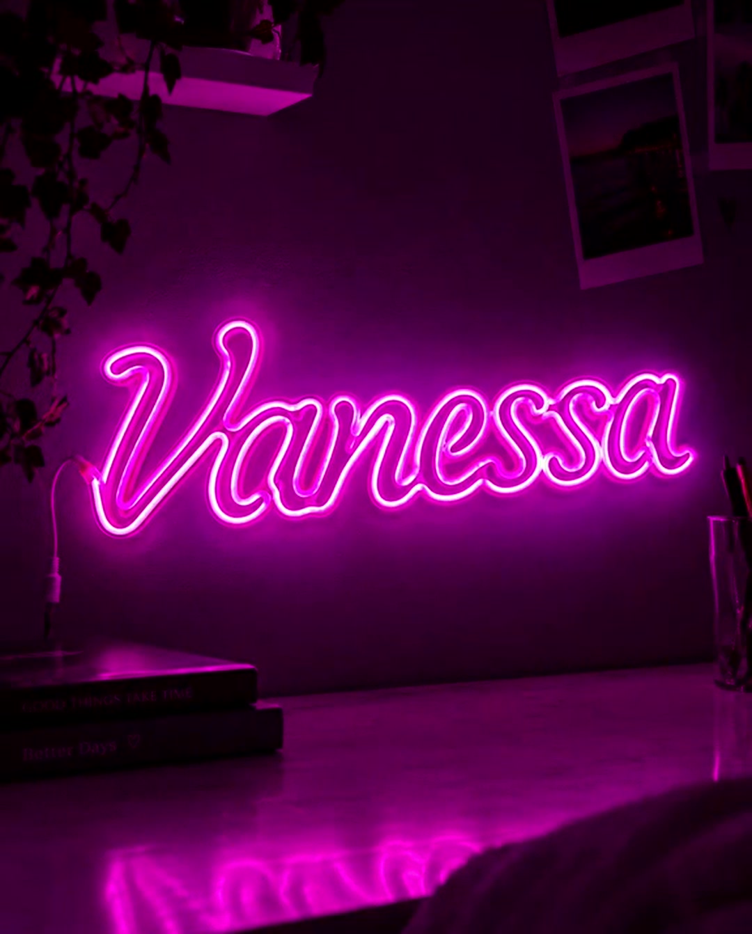 Scritta luminosa neon rosa con il nome Vanessa appesa alla parete sopra una scrivania